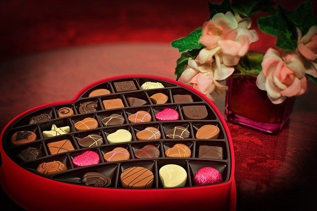 A heart shaped box of chocolates and flowers