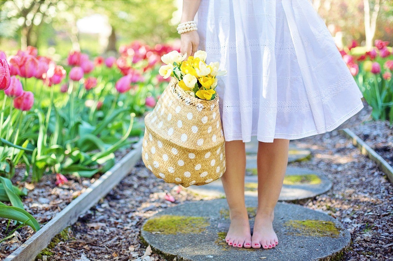 A woman wearing a white dress holding a bag with yellow roses