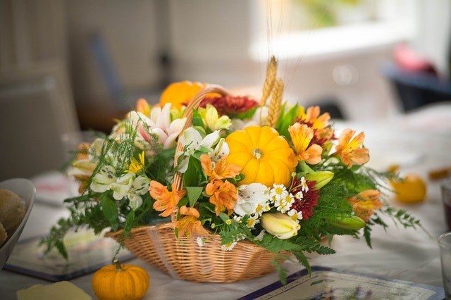 A basket of flowers and lush greens with mini pumpkins