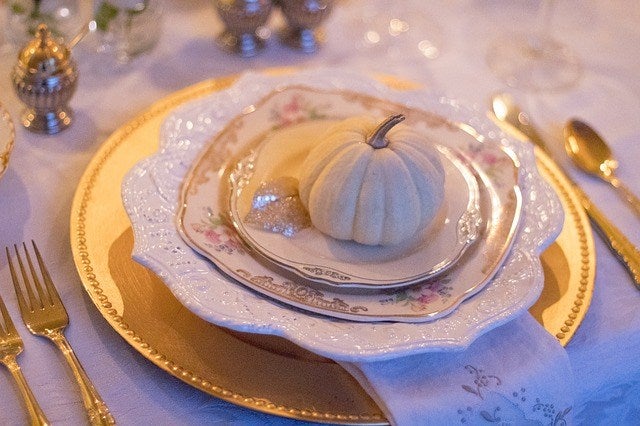 Elegant golden and silver table set up with white mini pumpkin