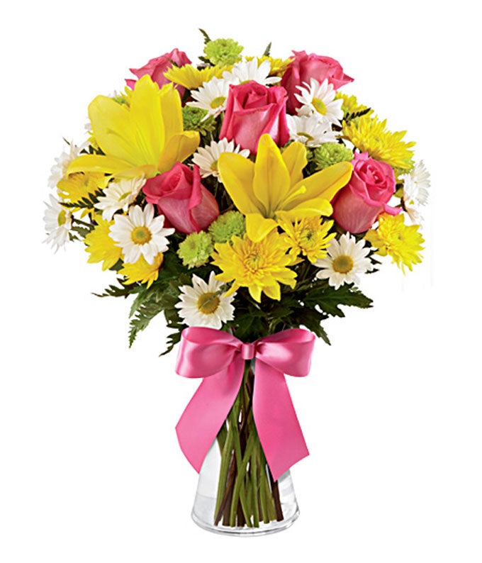 Yellow lilies, pink roses and yellow carnations in a vase with a bow