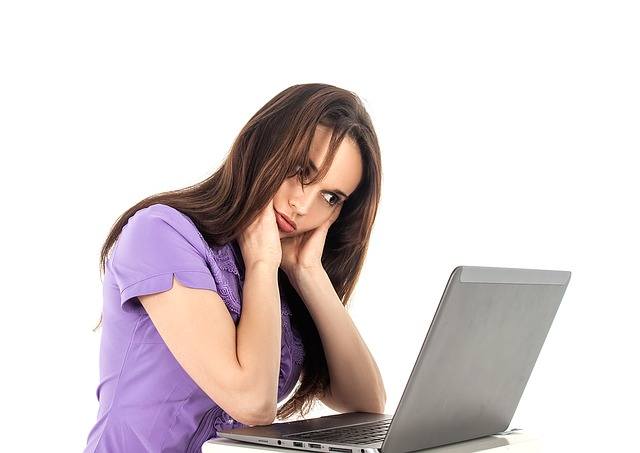 A woman wearing a purple t-shirt looking at a laptop computer