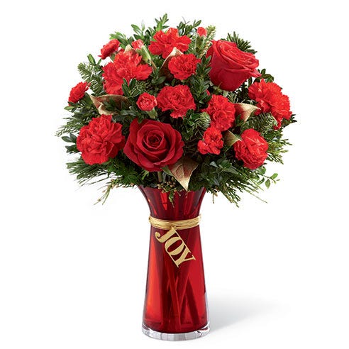 red roses and red carnations in a red glass vase that says Joy
