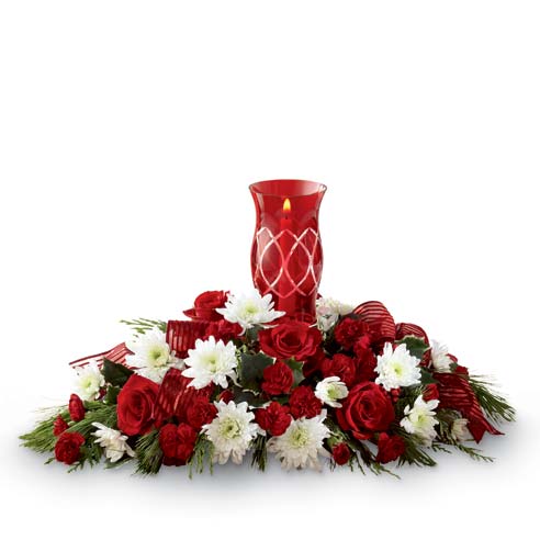 A  Centerpiece Bouquet including Red Roses, White Chrysanthemums, Burgundy Mini Carnations and Lush Holiday Greens in a Glass Hurricane Candle Holder with Single Taper Candle