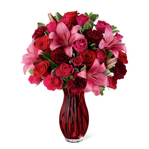 A Bouquet of Dark Pink LA Hybrid Lilies, Red Roses, Hot Pink Spray Roses, and Burgundy Carnations in a Sparkling Ruby-Colored Vase