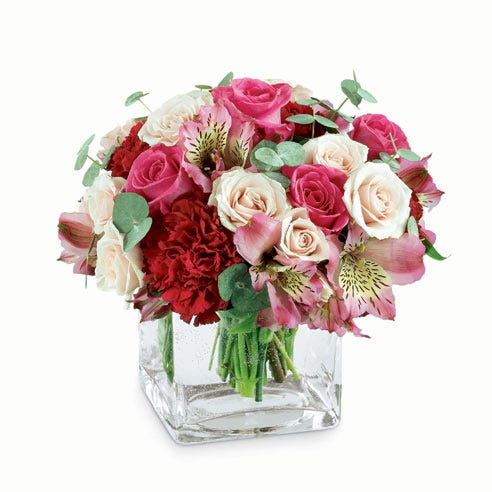 Romantic white roses, pink roses and red carnations in square glass vase