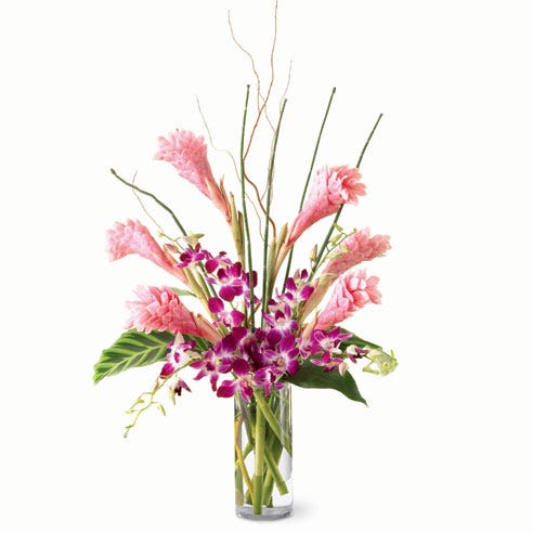 A modern pink ginger and orchid flower bouquet in a clear glass vase