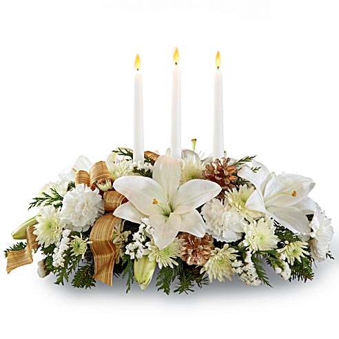 A centerpiece flower arrangement that includes White Lilies, White Carnations, Chrysanthemums, Gold Pinecones and Tapered Candles