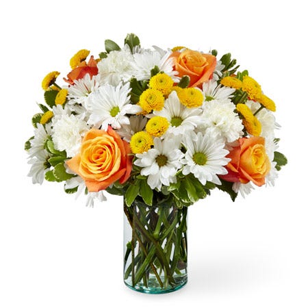 Orange rose white daisy and yellow button pom flower bouquet in a clear vase