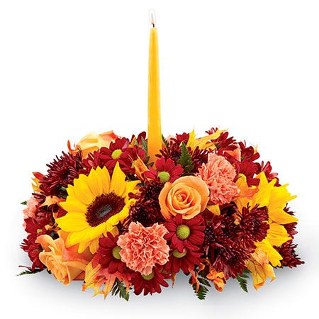 Fall floral centerpiece with sunflowers, orange roses and carnations and yellow candle