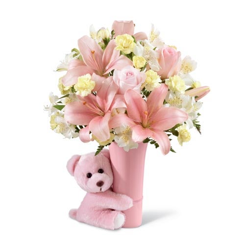 A Bouquet of Pastel Pink Roses, Pink Asiatic Lilies, Yellow Mini Carnations, White Peruvian Lilies and Lush Greens in a pink vase with a Hugging Teddy