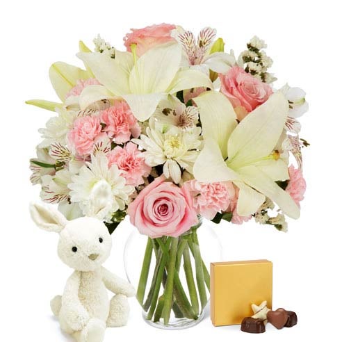 Easter bouquet with white lilies next to a plush bunny and Easter candy