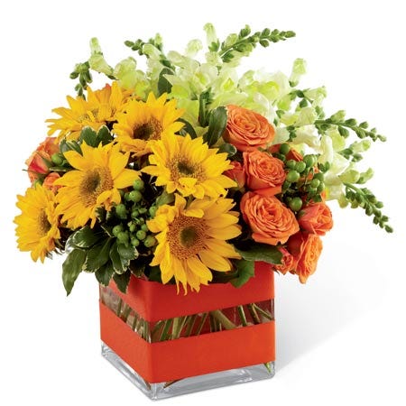 A floral combination of mini sunflowers, orange spray roses, yellow snapdragons, and green hypericum berries