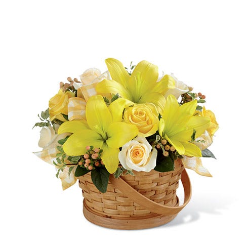 Yellow roses, cream roses, yellow LA hybrid lilies, peach hypericum berries and greens in a woven woodchip handled basket
