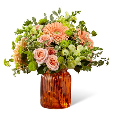 Pastel orange gerbera daisies with orange spray roses in an orange vase