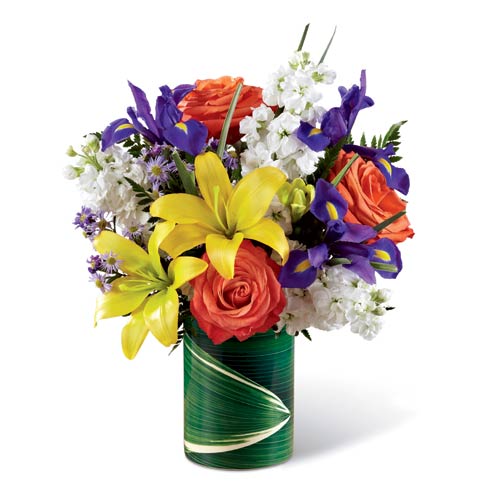 Yellow lily orange rose and white stock flowers bouquet in a leaf wrapped vase