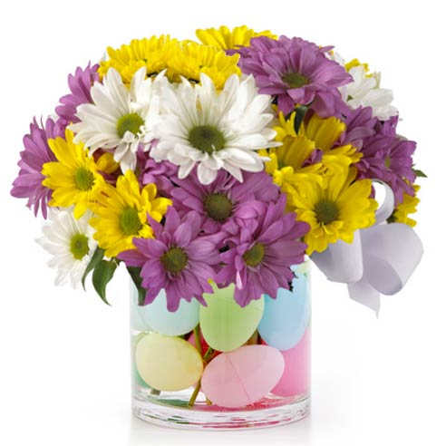 A Bouquet of Lavender Daisies, Yellow Daisies and White Daisies in a Clear Glass Vase with Plastic Easter Eggs