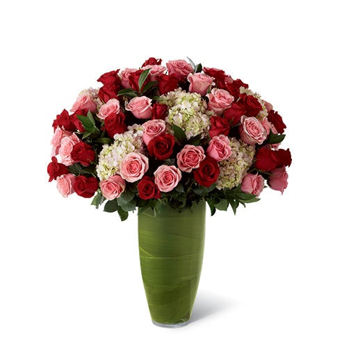 A Bouquet of Red Roses, Pink Roses, Pink Hydrangea, and Lush Greens in a Clear Glass Bullet Vase