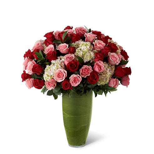 Premium long-stemmed red roses, premium long-stemmed pink roses, pink hydrangea, lush greens, and exotic foliage in a superior 14-inch clear glass bullet vase