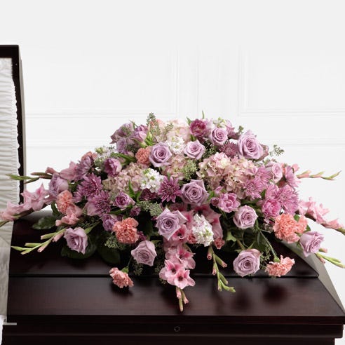 Purple and pink flowers delivered in a casket spray