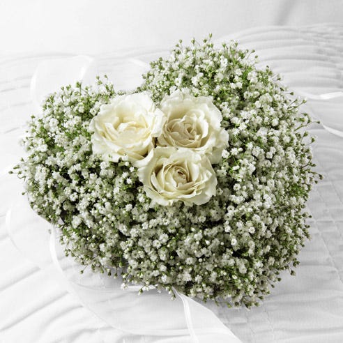 Baby's breath and white spray roses in a heart-shaped arrangement