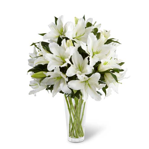 White oriental lilies and greens arranged in glass vase