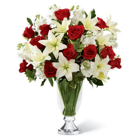 A bouquet of Red Roses, White Lilies, and Holiday Greens in a Glass Vase