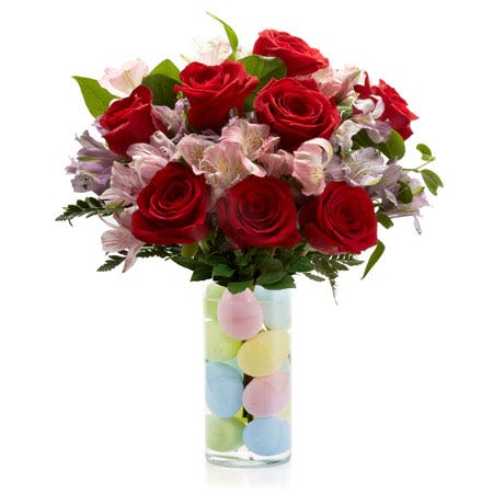 A Bouquet of Red Roses, Pink And Purple Alstroemeria, and Fresh Greens in a Glass Vase with Plastic Easter Eggs
