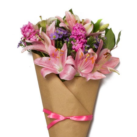 Paper wrapped pink lily and pink stock flowers bouquet with brown paper and ribbon