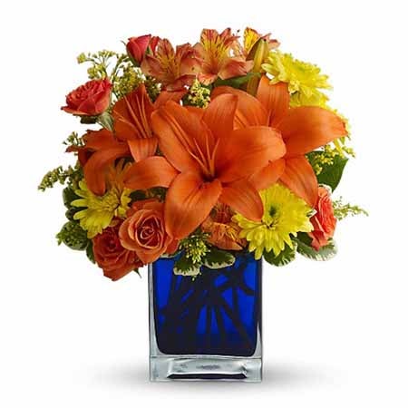 A Bouquet of Orange Asiatic Lilies, Orange Spray Roses, Orange Alstroemeria, Yellow Cushion Spray Mums, and Solidago in a Blue Cube Vase