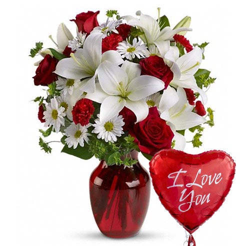 A Bouquet of Red Roses, White Asiatic Lilies, White Daisy Spray Mums, and Red Mini Carnations in a Red Glass Vase with 1 Love-Themed Mylar Balloon