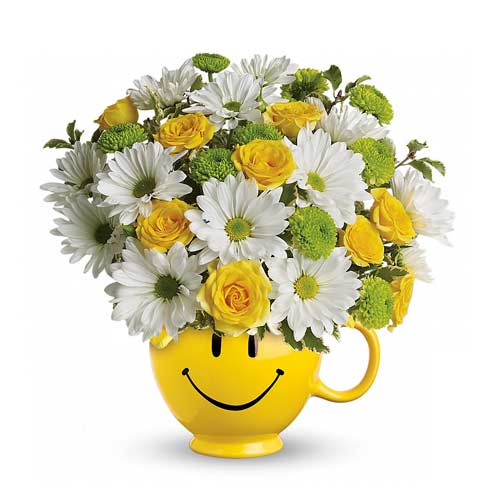 A bouquet of White Daisy Flowers, Yellow Roses, and Green Chrysanthemums Button Sprays on a Smiley Face Coffee Mug