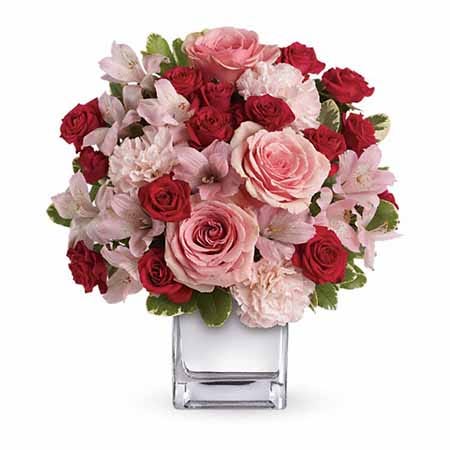 Pink roses, red spray roses and pink alstroemeria in a square vase
