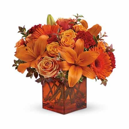 A Bouquet of Orange Roses, Orange Gerbera Daisies, Red Mini Carnations and Red Huckleberry in an Orange Glass Vase