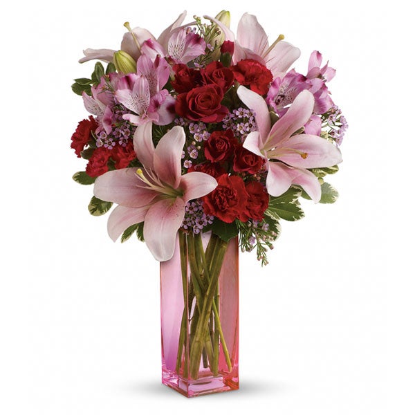 A Bouquet of Red Roses, Light-Pink Asiatic Lilies, Mini Crimson Carnations, Flush Alstroemeria, Pittosporum, and Hot-Pink Waxflower in a Blush Hued Vase