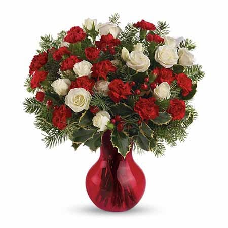 White spray roses and red mini carnations with holly in a red vase