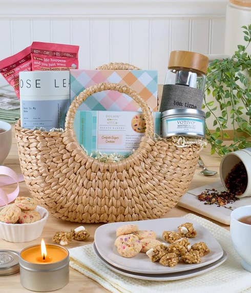 Gift basket with tea infuser, loose leaf tea, sugar cookies, granola bites, aromatic candle, and water hyacinth basket with personalized card message.