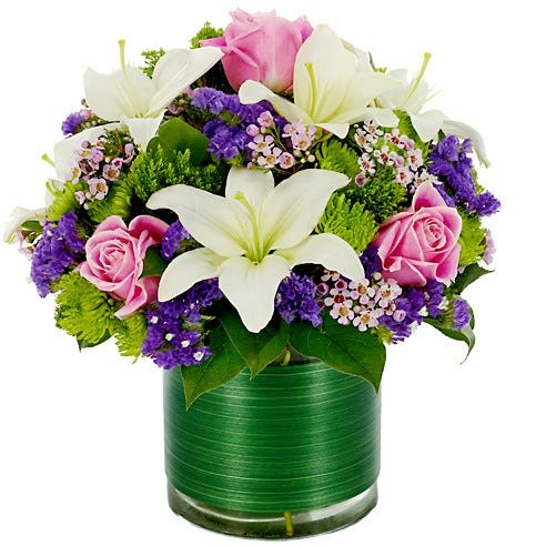 Pink Roses, white lilies and purple flowers arranged in a circular glass vase