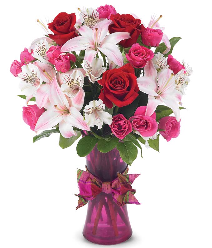Red roses, pink roses, white alstroemeria and light pink lilies in a purple vase