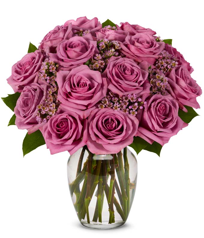 Lont stem purple roses with purple waxflower in glass vase