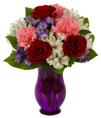 Red roses, pink carnations and white flowers in a purple vase