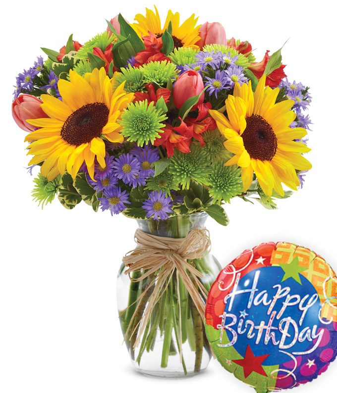 A Bouquet of Large Sunflowers, Red Tulips, Green Button Poms, Red Alstroemeria, Purple Alstroemeria, and Purple Monte Casino Asters  on  a Glass Vase with 1 Piece Birthday Themed Mylar Balloon and Decorative Ribbon