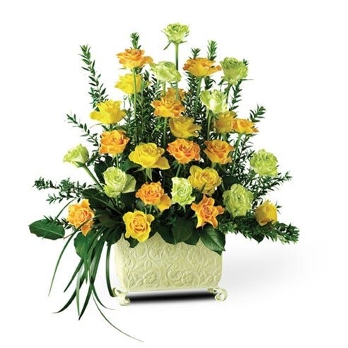 Yellow roses, orange roses and greenery in embossed container