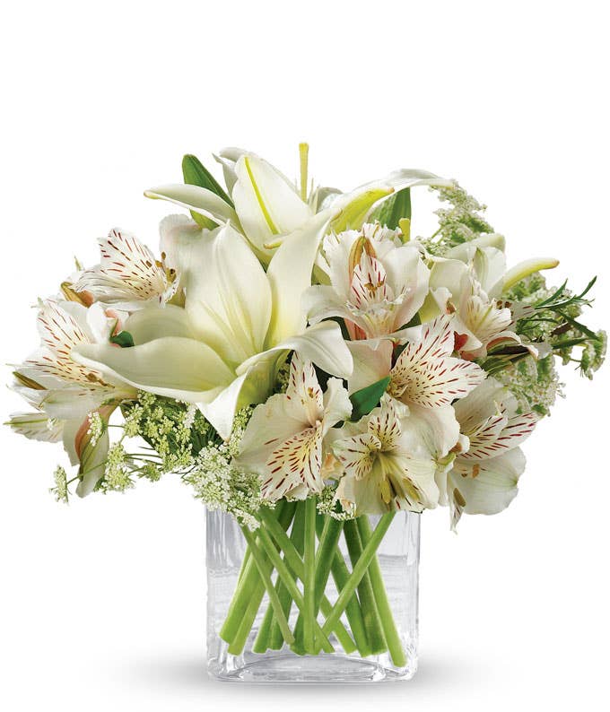 White sympathy flowers in clear cube vase