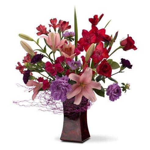 Red roses, pink roses, and purple flowers in red vase