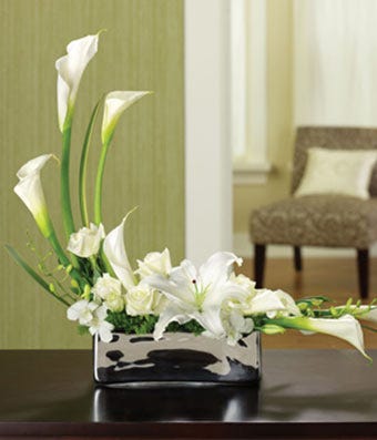 White roses, calla lilies and orchids in silver planter