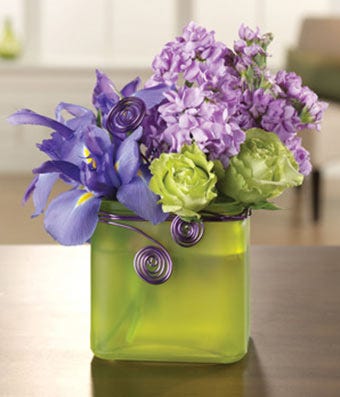 Purple irises arranged with green roses in a square vase