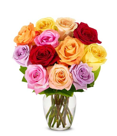 Bouquet of multicolored roses in shades of red, pink, peach, yellow, and lavender arranged in a clear glass vase with visible stems. 