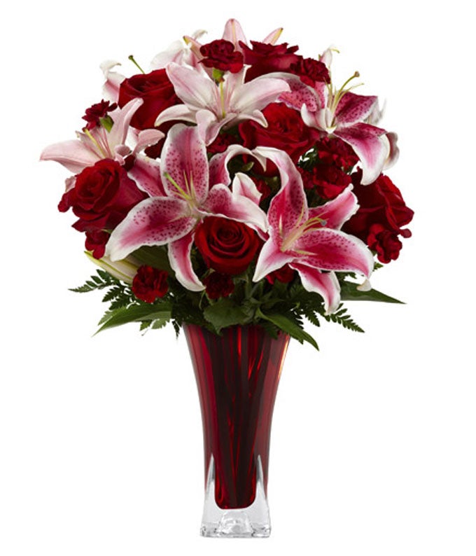 A bouquet of Stargazer Lilies, Red Roses, Burgundy Mini Carnations and Pink Asiatic Lilies on Decorative Glass Vase