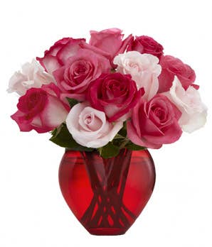 Heart shaped mixed fuchsia and pink roses bouquet in a red glass vase